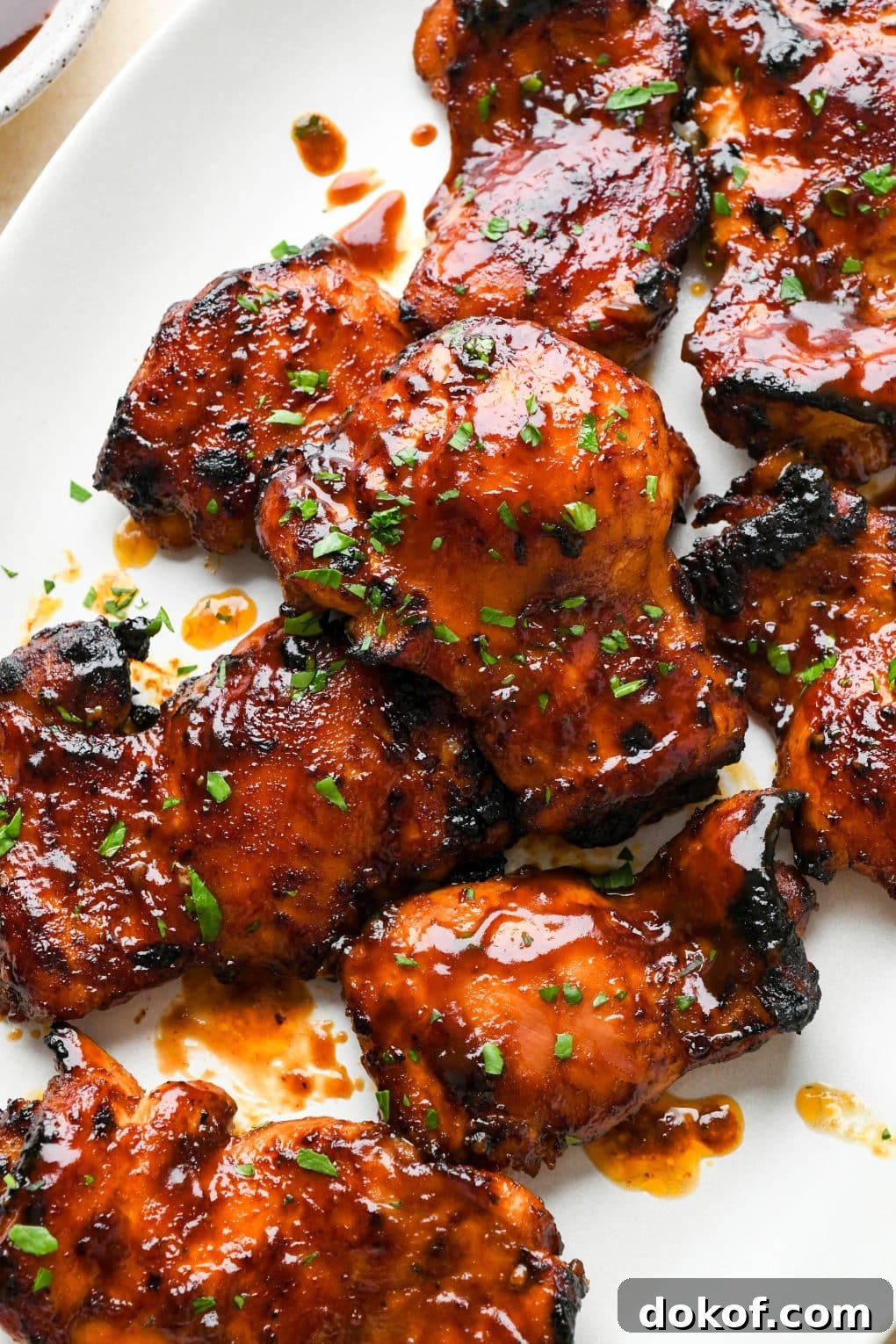 Oven-Baked Caramelized BBQ Chicken Thighs with Sticky Glaze 3 Baked bbq chicken thighs on a large white oval platter.