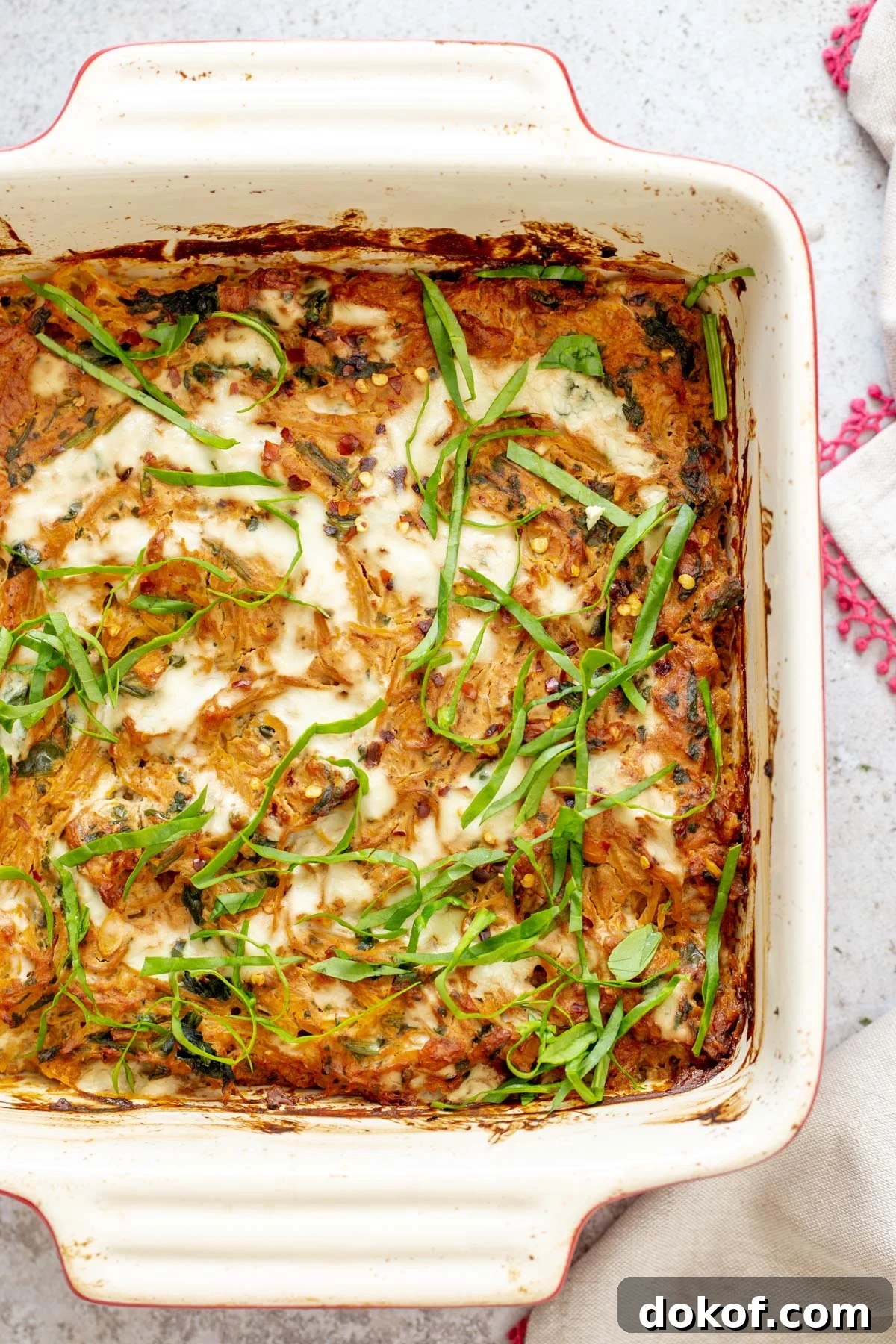 overhead shot of a casserole dish with vegan spaghetti squash bake sprinkled with fresh chopped basil 