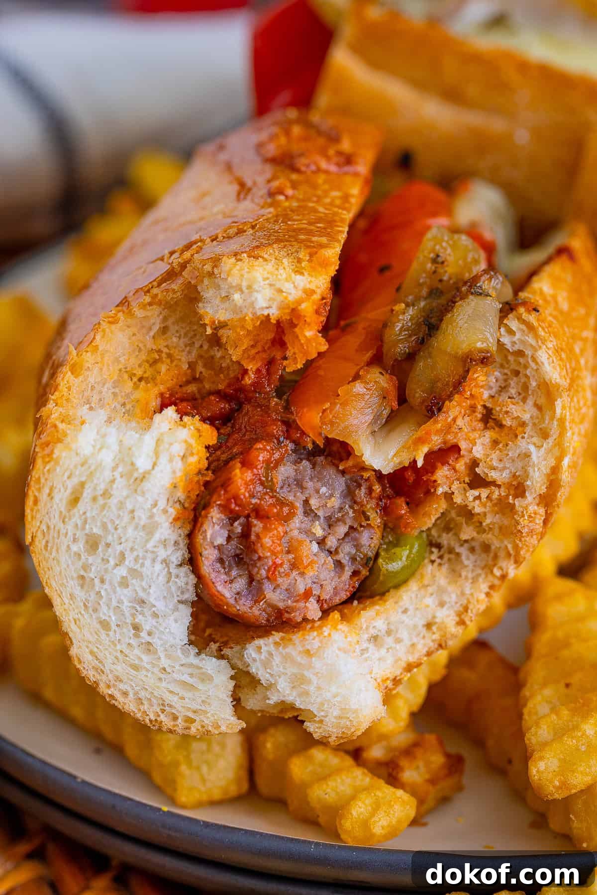 A cross-section of an Italian sausage sandwich showing the grilled sausage, peppers, and melted cheese.