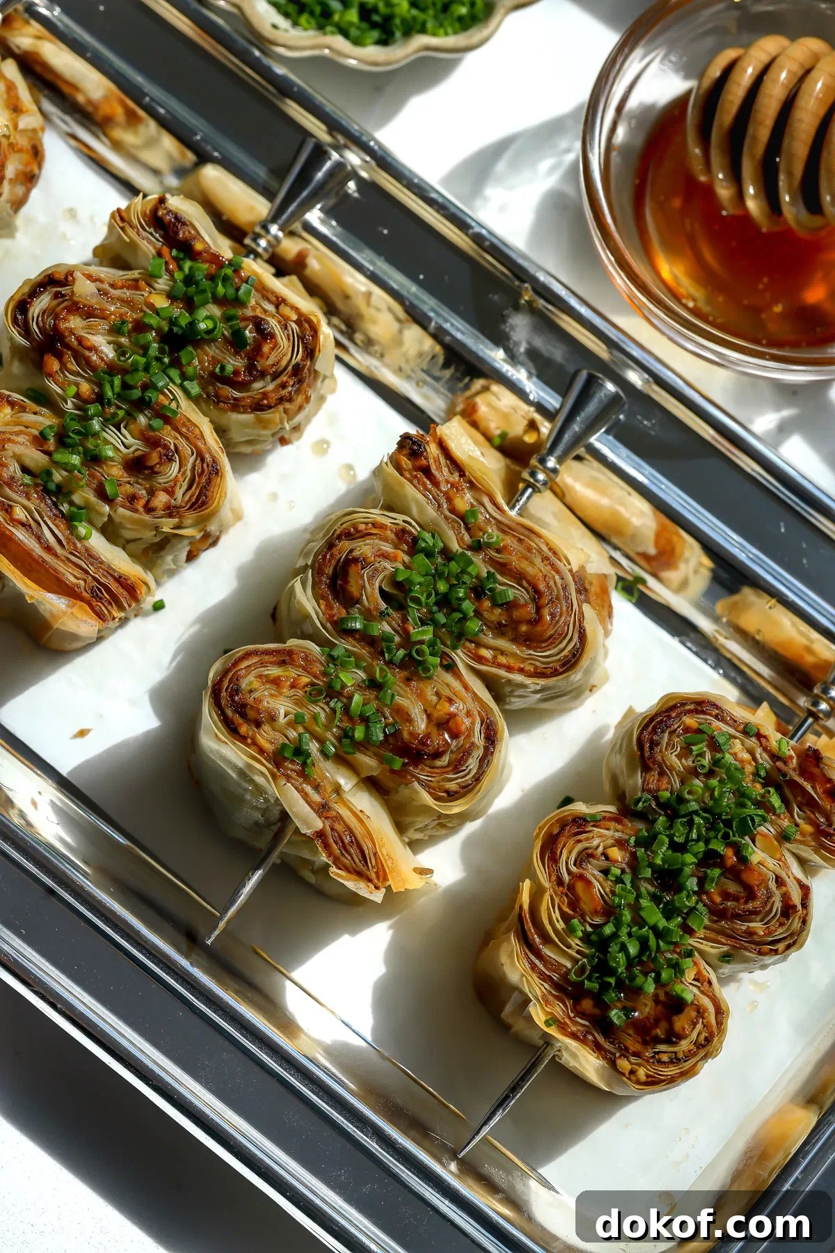 Overhead view of crispy phyllo with whipped feta and honey appetizers arranged on a silver tray.