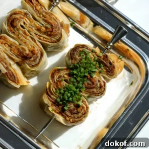 Vertical close up of crispy phyllo skewers with whipped feta and fresh chives on a silver tray.