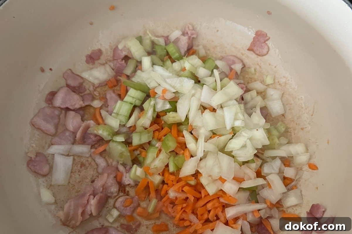 Vegetables and bacon cooking in a large dutch oven.
