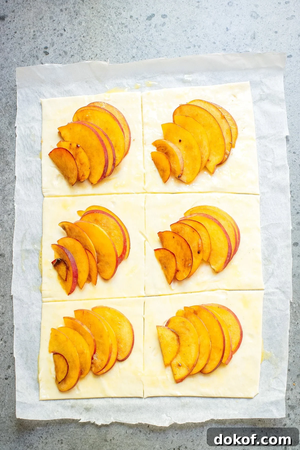 Flaky Peach Puff Pastry Tart Recipe for Summer Dessert 7 An overhead image of adding fresh peaches on each puff pastry.