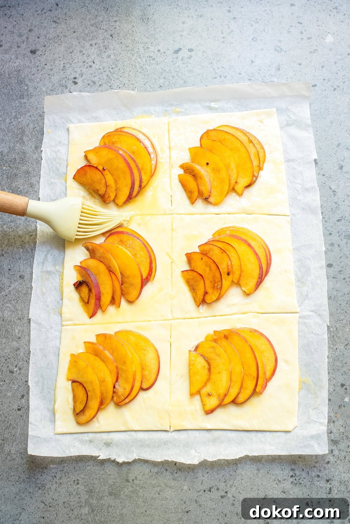 Flaky Peach Puff Pastry Tart Recipe for Summer Dessert 8 An overhead image of brushing the peaches with an egg wash.