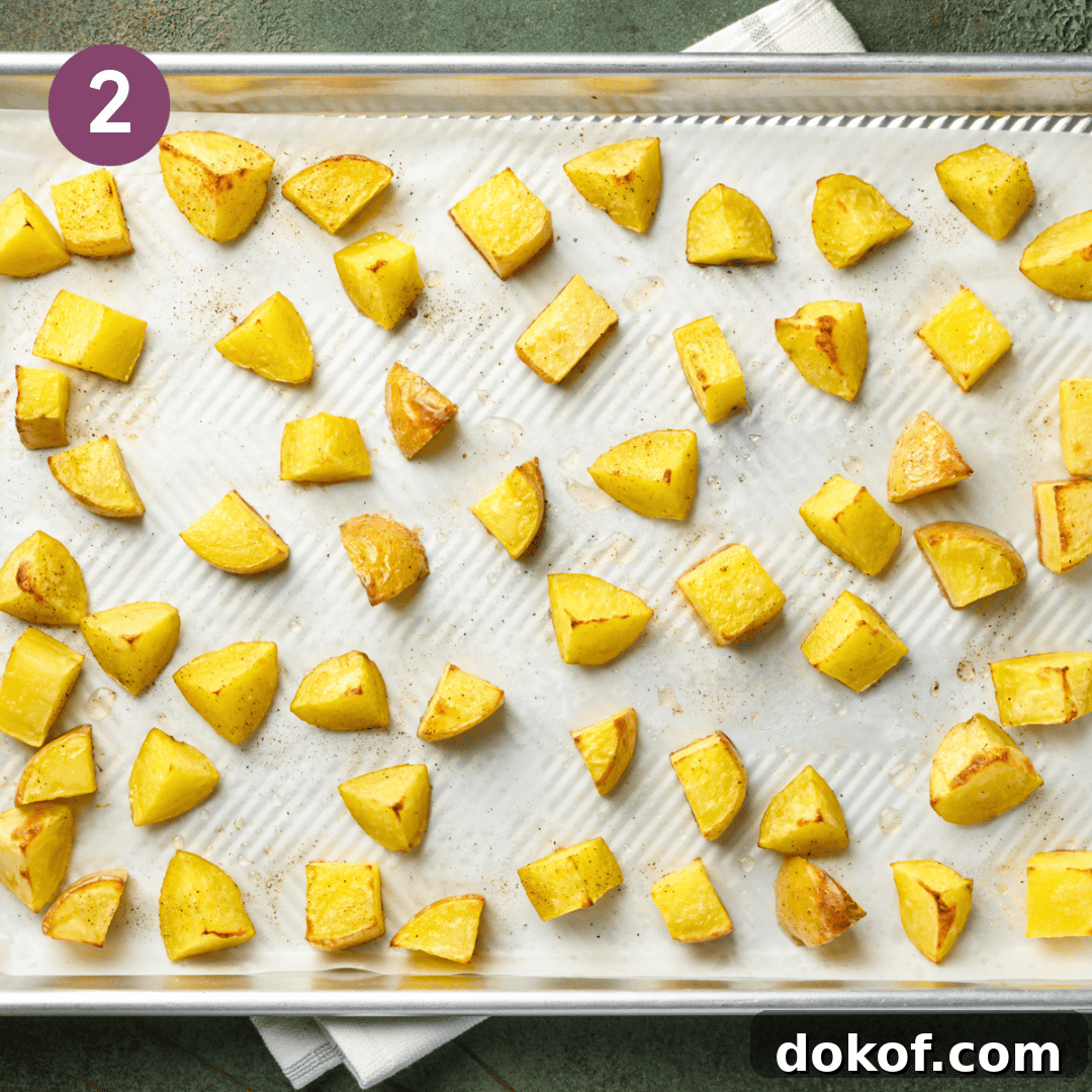 cooked cubed potatoes on a lined baking tray.