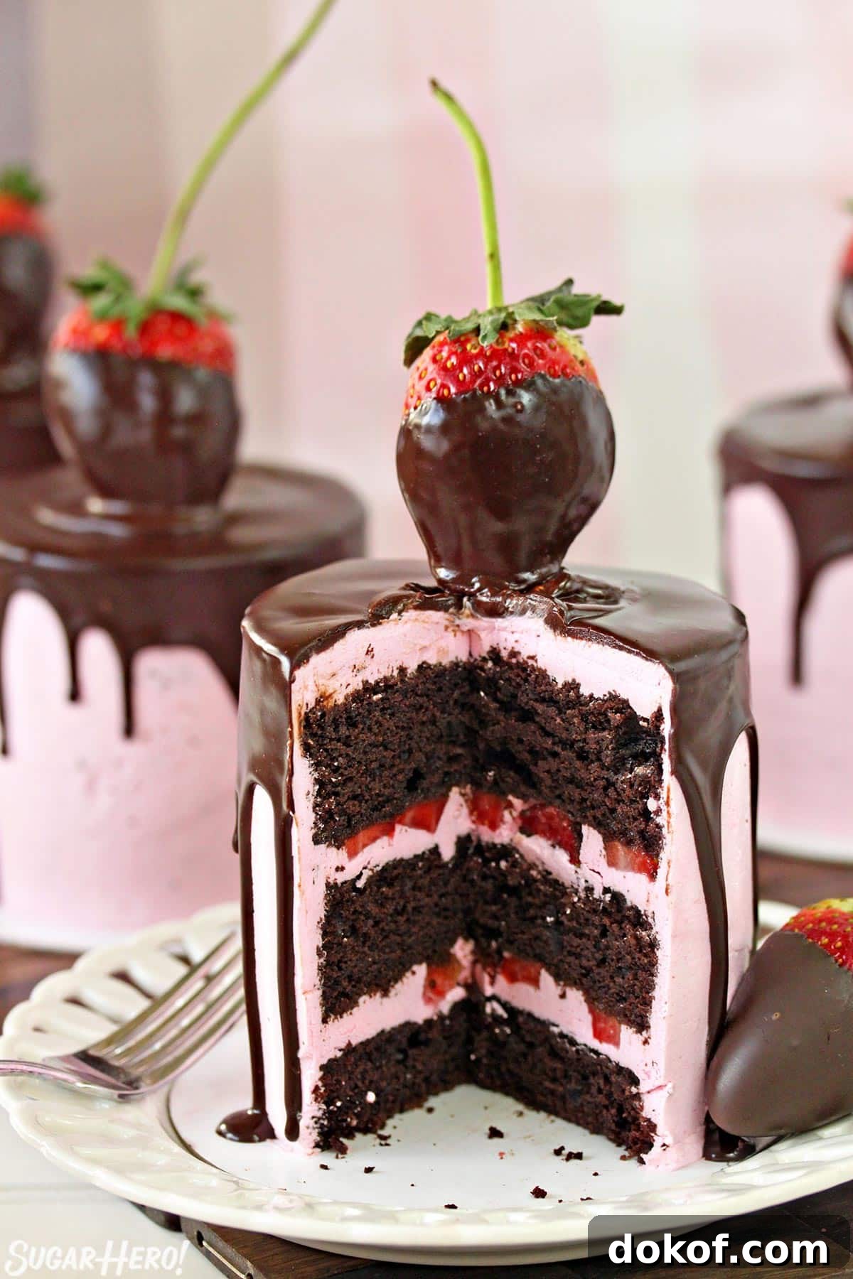 Chocolate-Covered Strawberry Cake on a white plate, cut open to show the cake and buttercream layers inside.