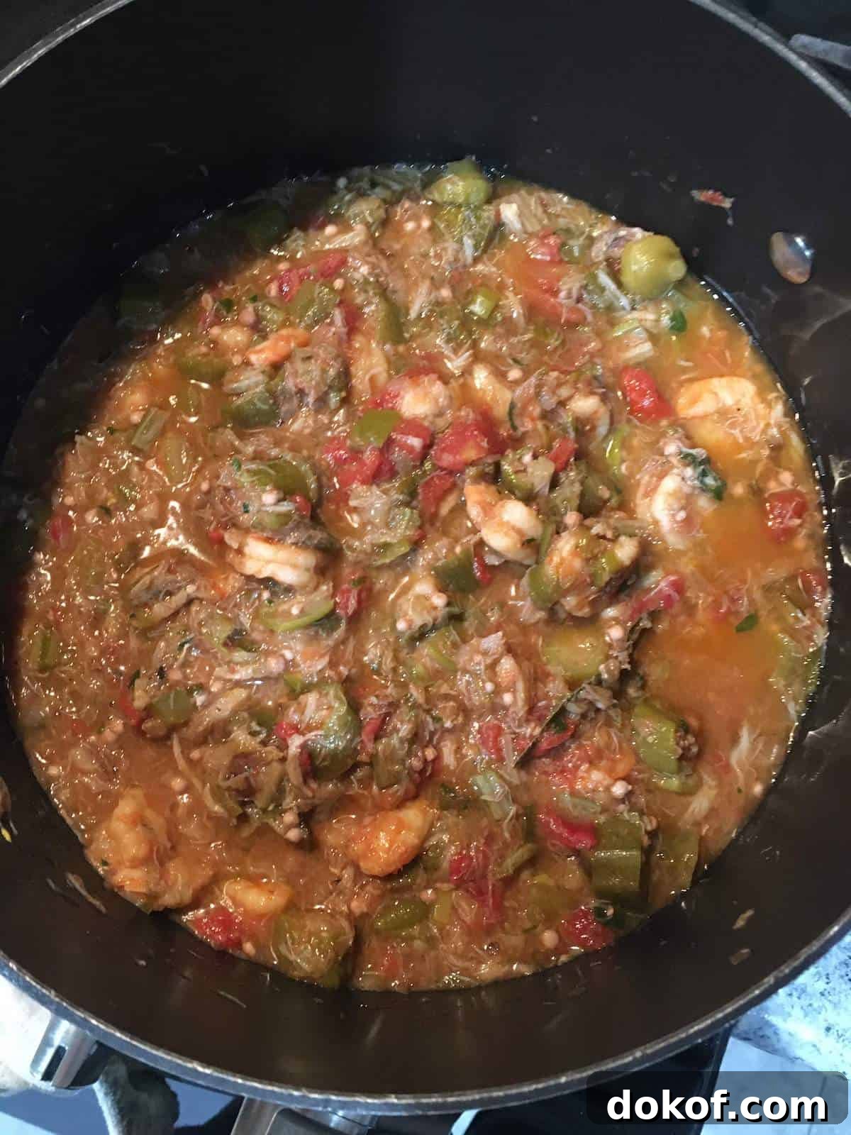 Seafood gumbo simmering in a black pot.