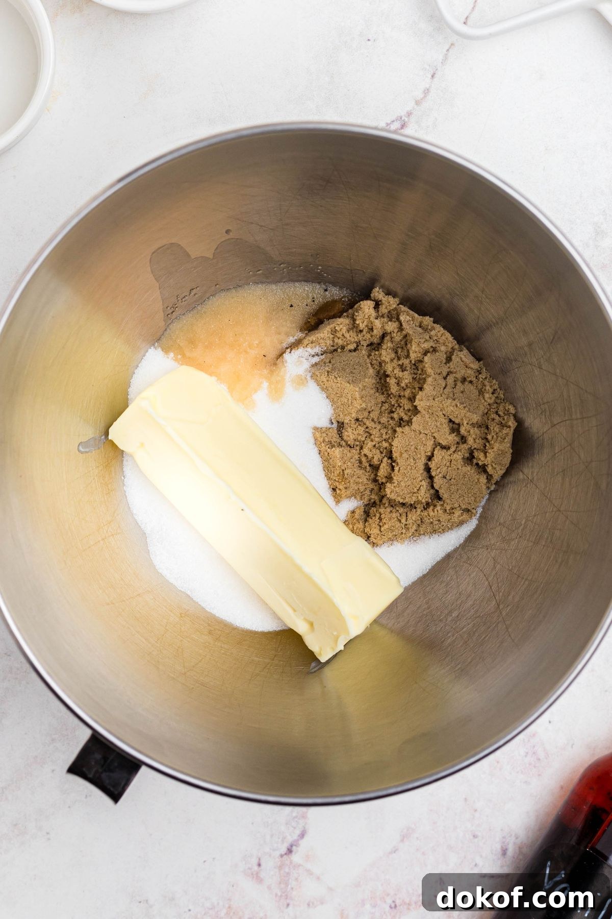 Butter and sugars being mixed together in a silver mixing bowl. 