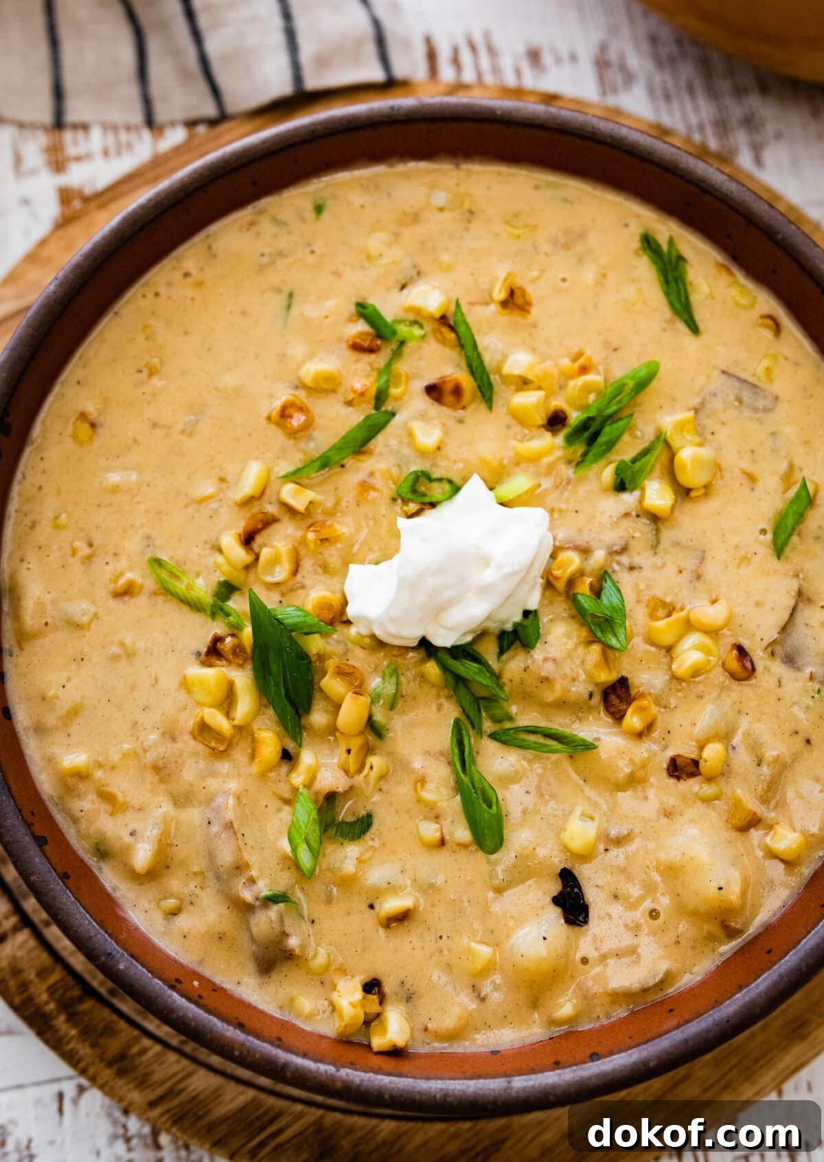 bowl of potato corn chowder recipe with sour cream and green onions on top ready to eat.