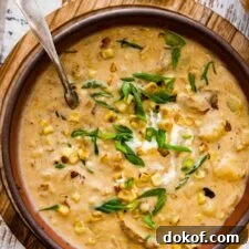 bowl of potato corn chowder recipe with sour cream and green onions on top ready to eat. Spoon in the bowl.