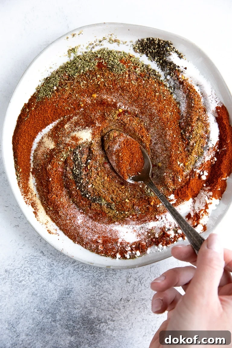 Mixing together the herbs and spices on a white plate to make homemade taco seasoning.