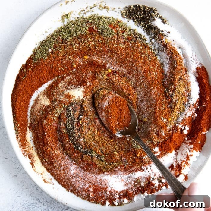 Shallow white bowl filled with various different seasonings mixing together.