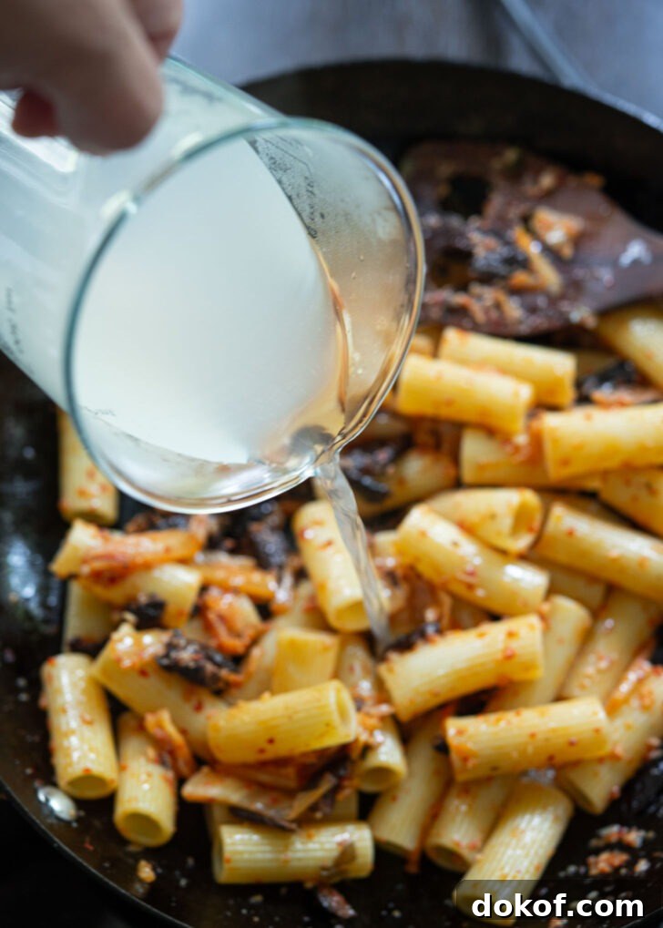 Pasta water is added to kimchi olive pasta.