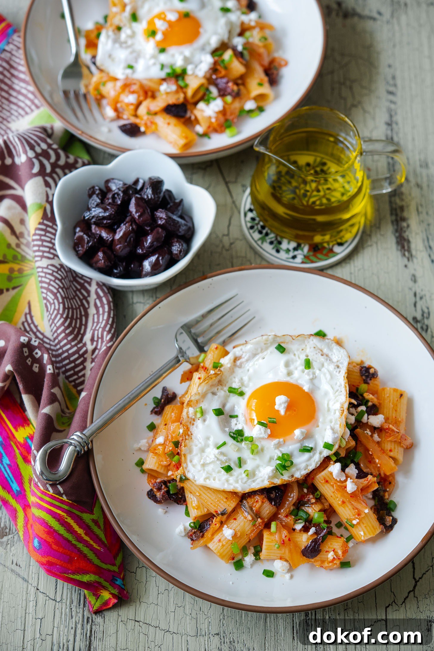 Mediterranean-Korean fusion style kimchi olive pasta topped with fried egg and feta cheese.