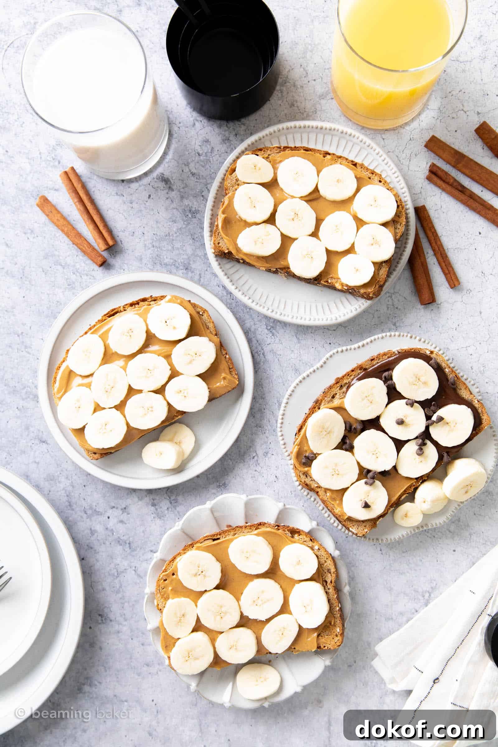 four plates with toast adorned in peanut butter and banana slices