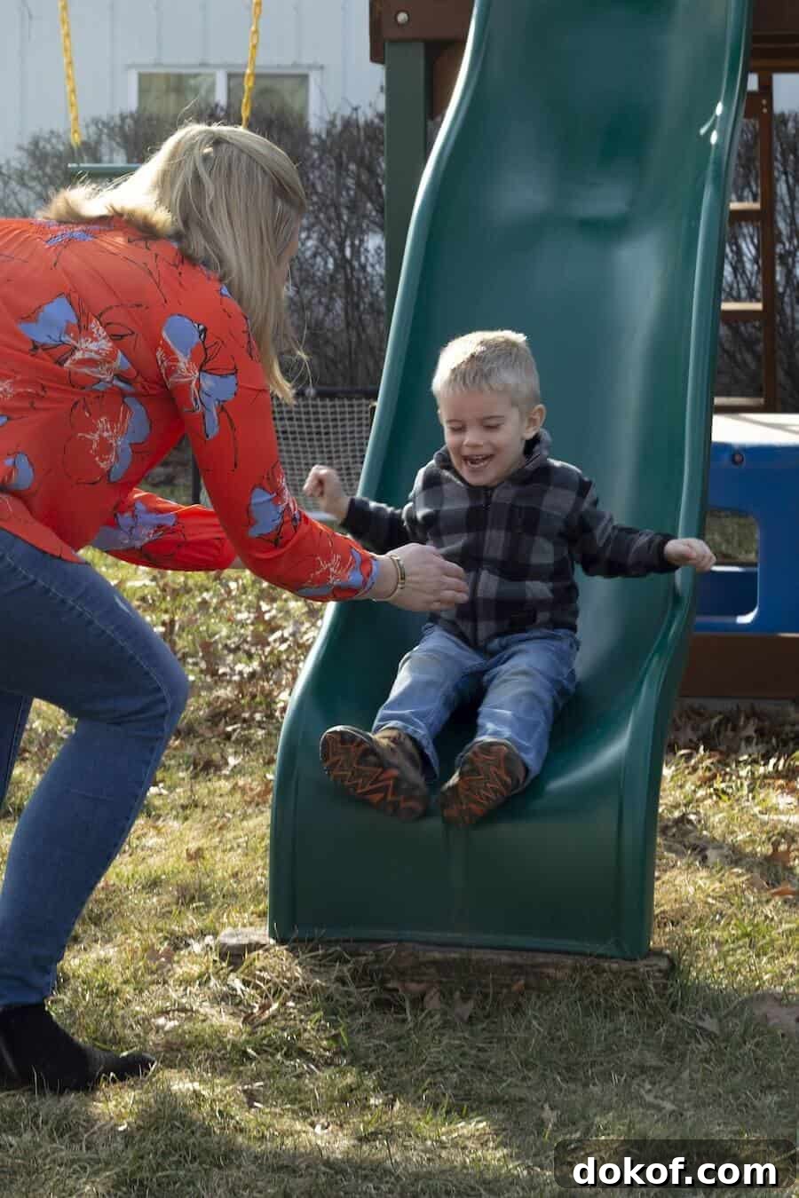 A boy laughing as he rides a slide.