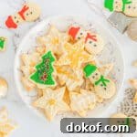 Decorated Christmas sugar cookies with icing and sprinkles on serving plate with additional cookies scattered around table