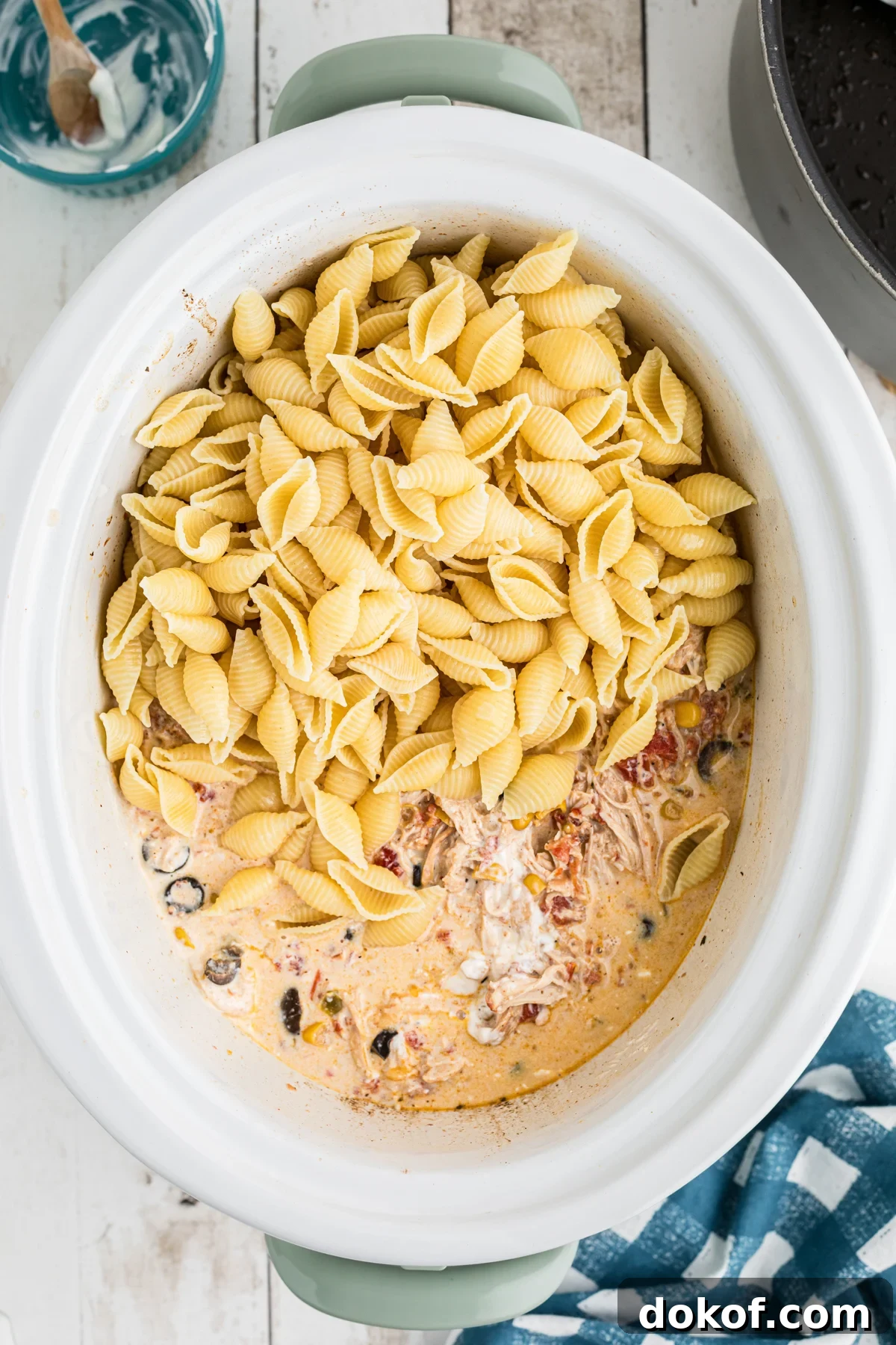 Southwestern Cheesy Chicken Pasta Bake with Roasted Corn and Peppers 6 shell pasta added to the cooked sauce and chicken in the slow cooker.