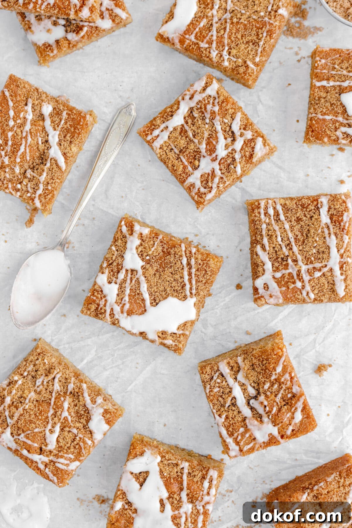 overhead shot of cinnamon roll blondies on parchment paper with spoon of icing beside.