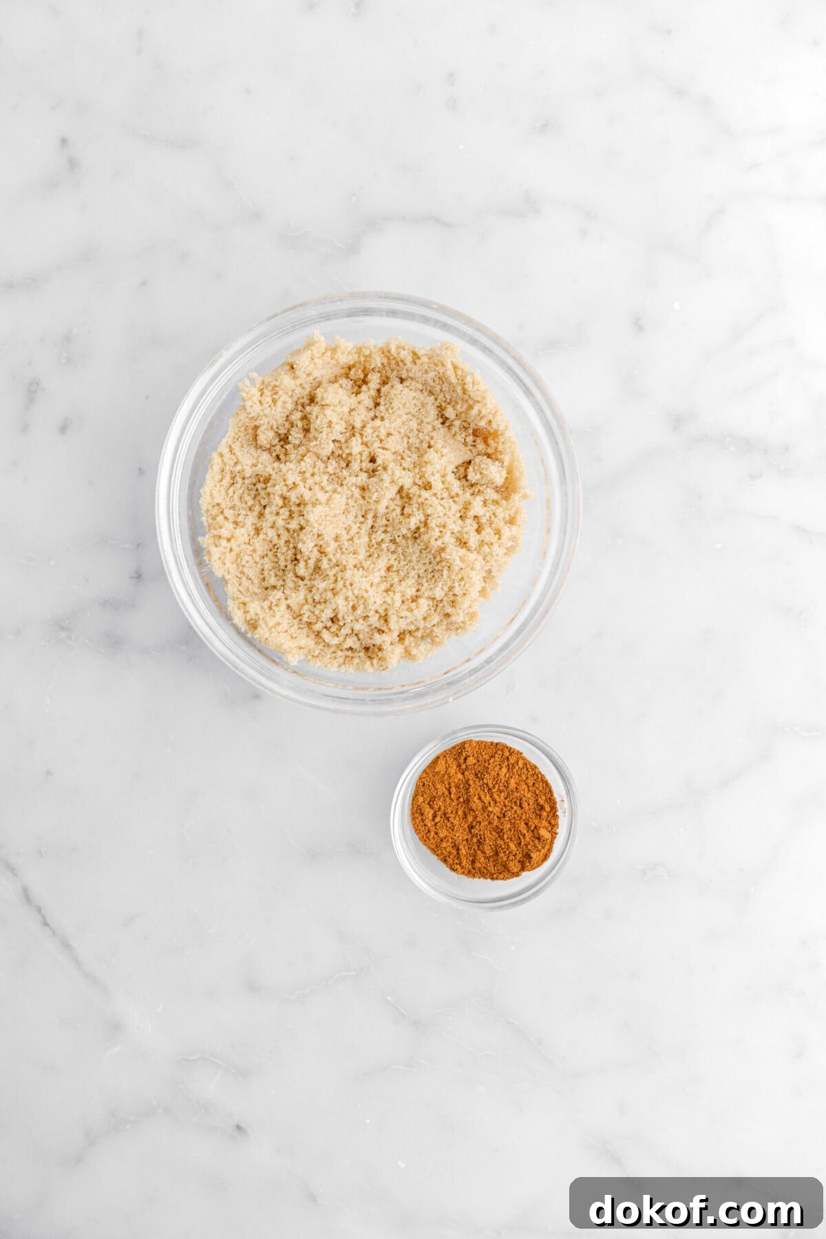 brown sugar and cinnamon in two separate bowls on marble surface.