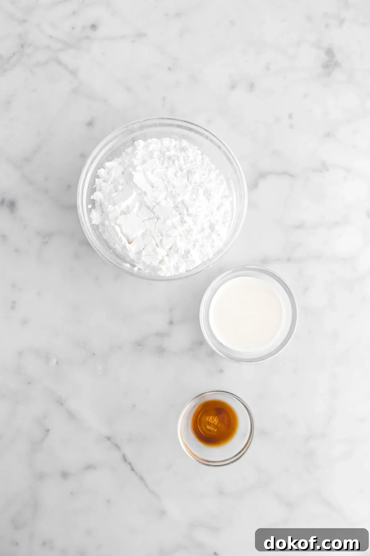 powdered sugar, milk, and vanilla on marble surface.