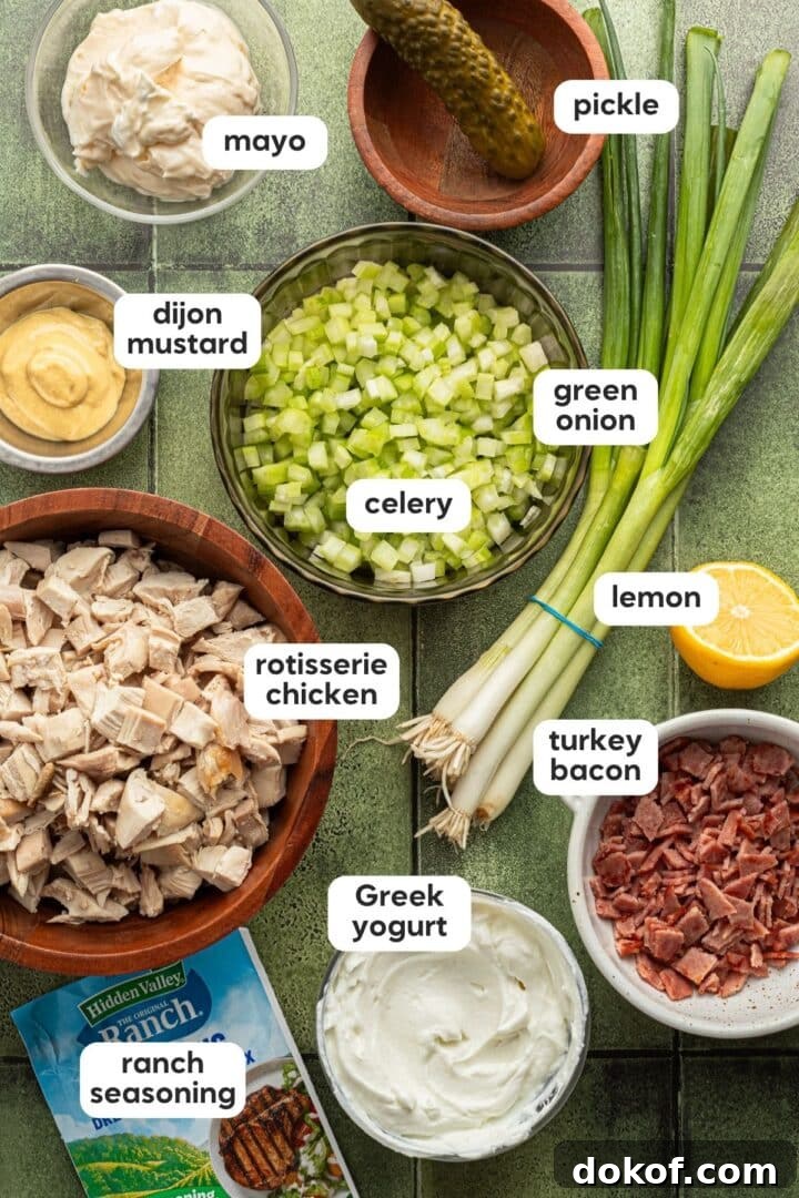 Ingredients for ranch chicken salad displayed in small bowls on a green tile counter.