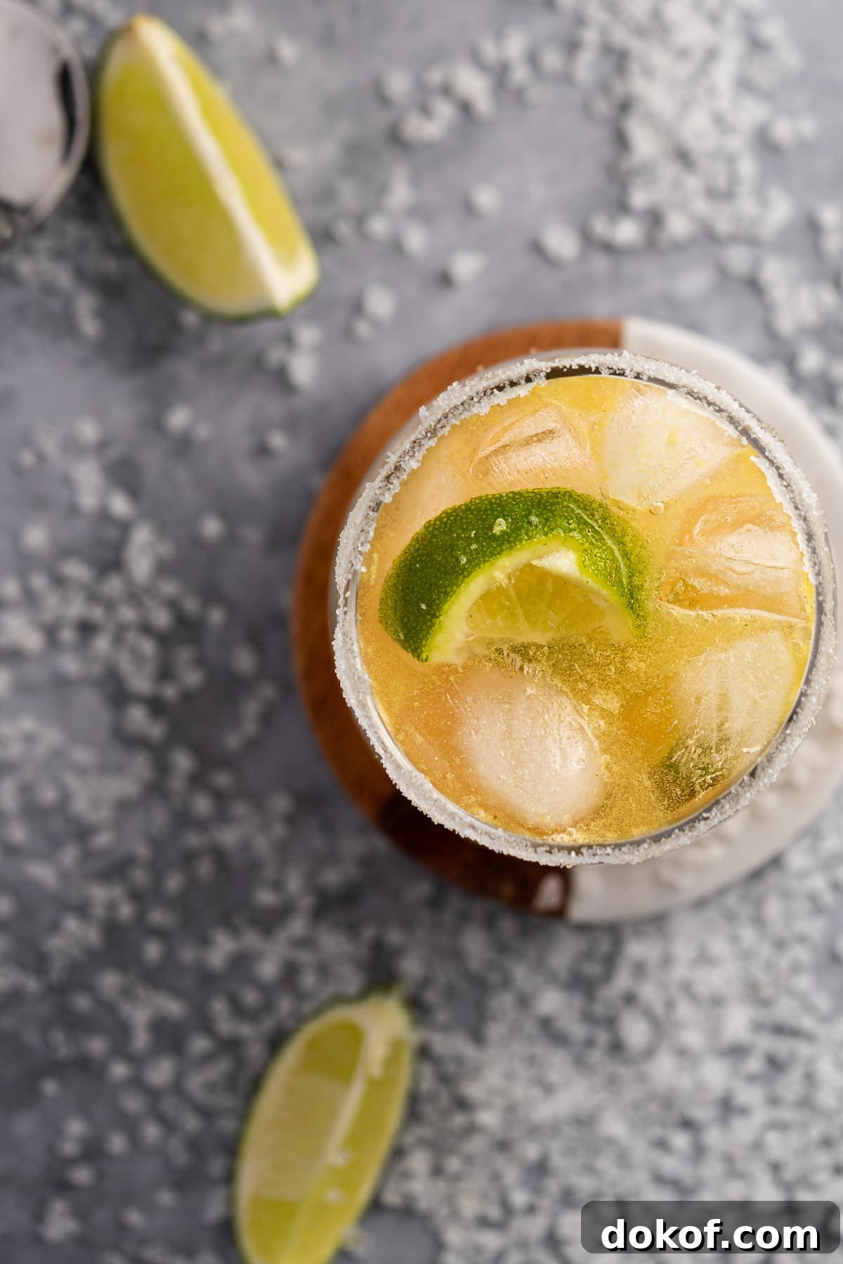 Overhead view of a margarita made with whiskey, on a table scattered with lime slices and salt.