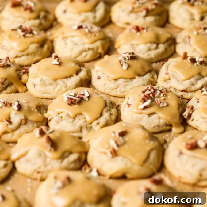 Close-up view of many rows of praline cookies topped with pecan pieces.