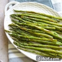 Overhead of cooked asparagus on white platter.