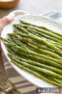 Hands holding serving platter of asparagus.