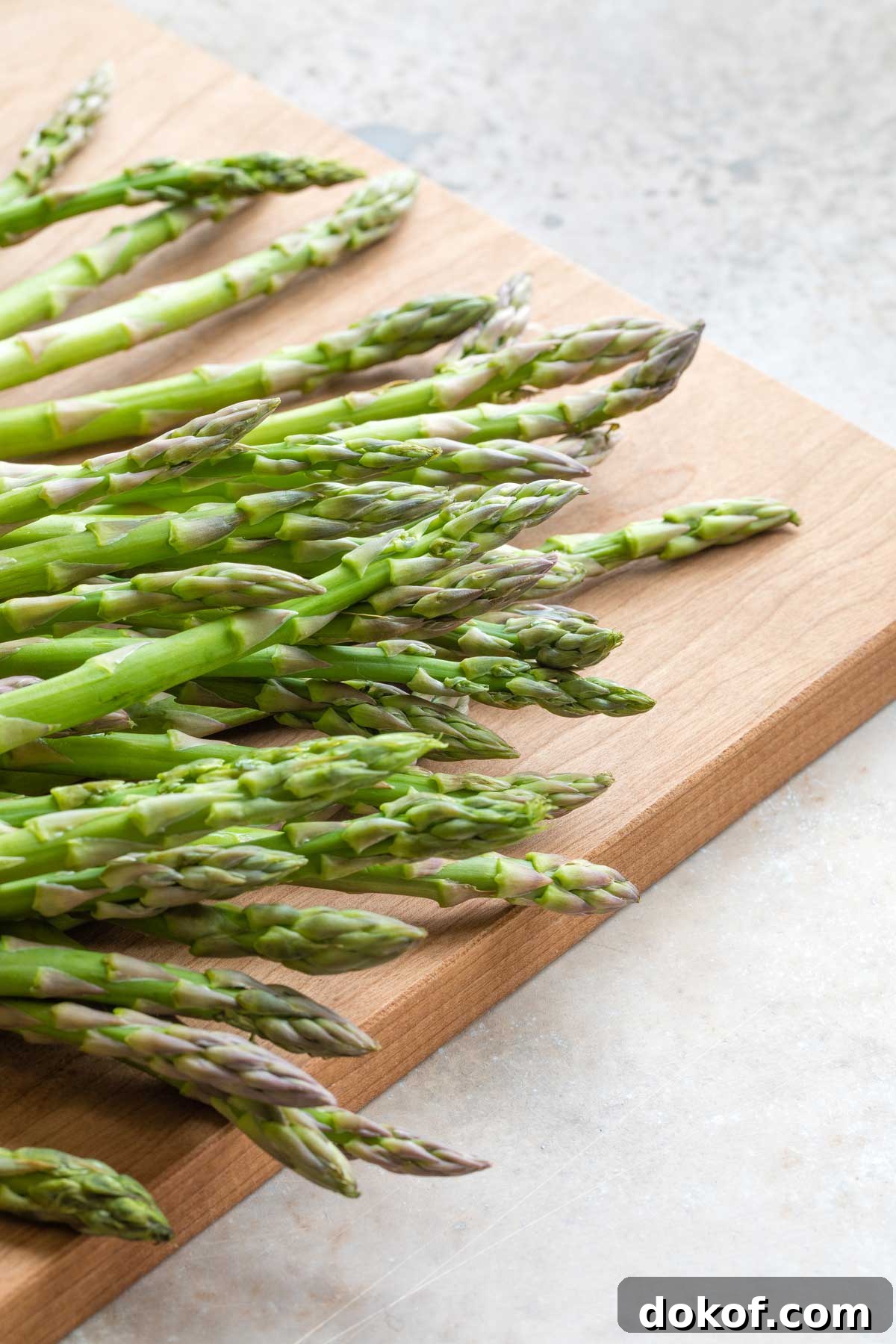 Fresh, raw asparagus on cutting board before prep.