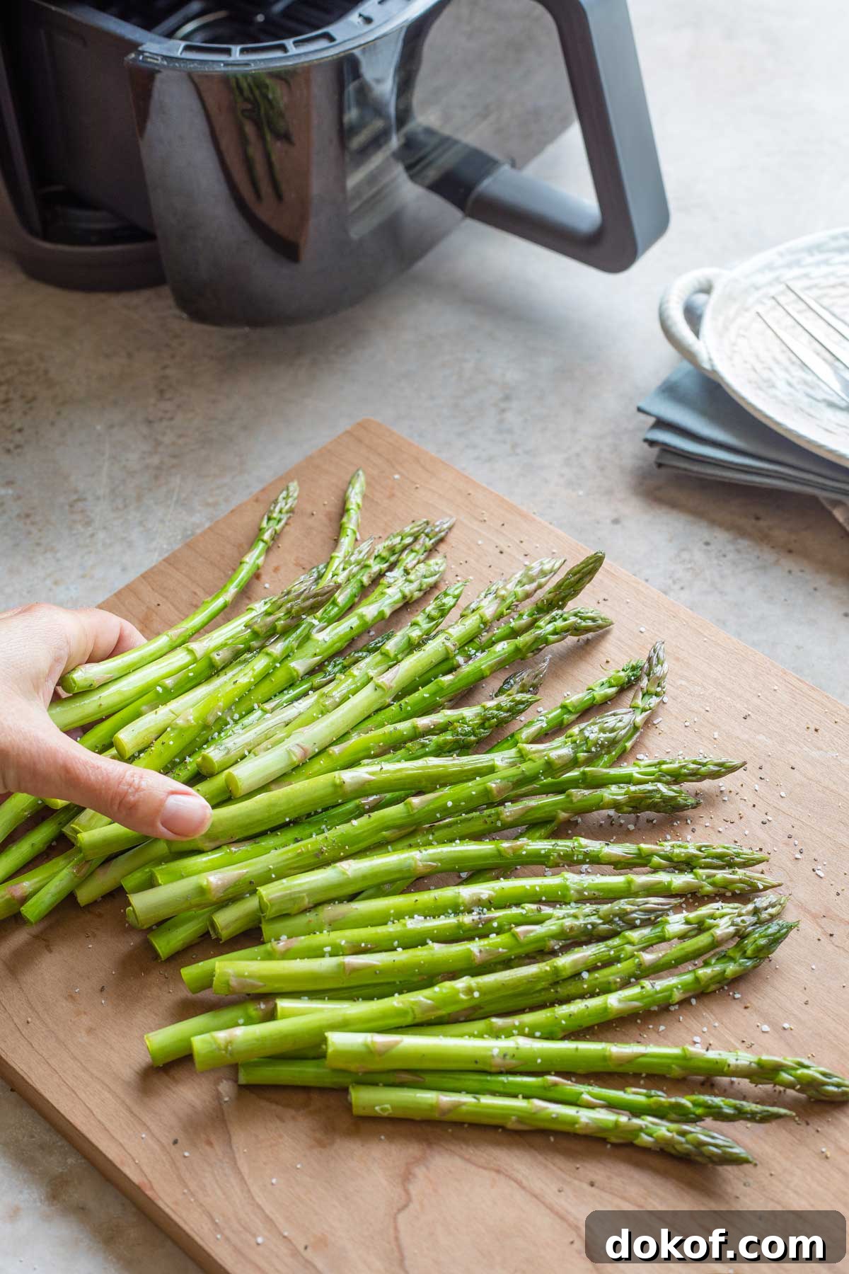 Hand tossing asparagus with oil and seasonings.