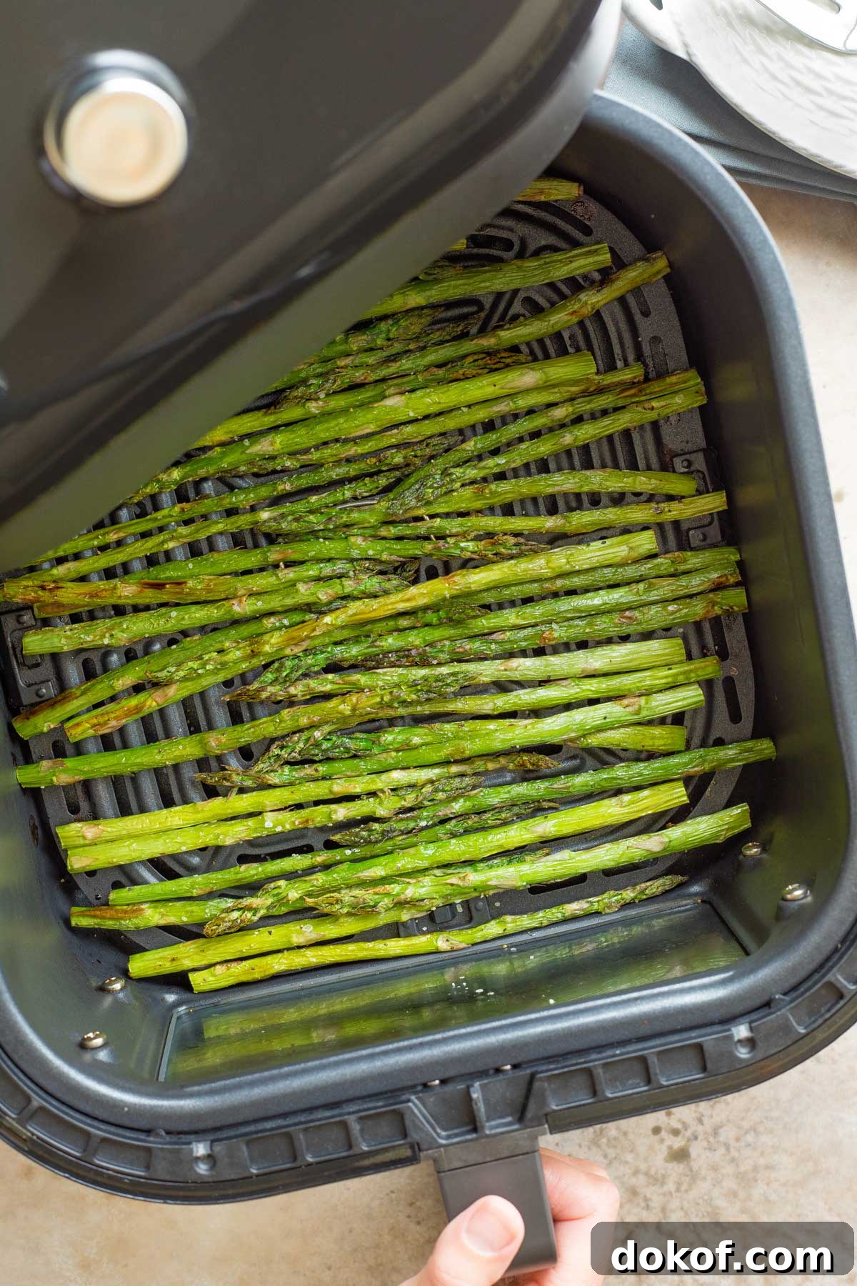 Air fryer drawer with cooked asparagus.