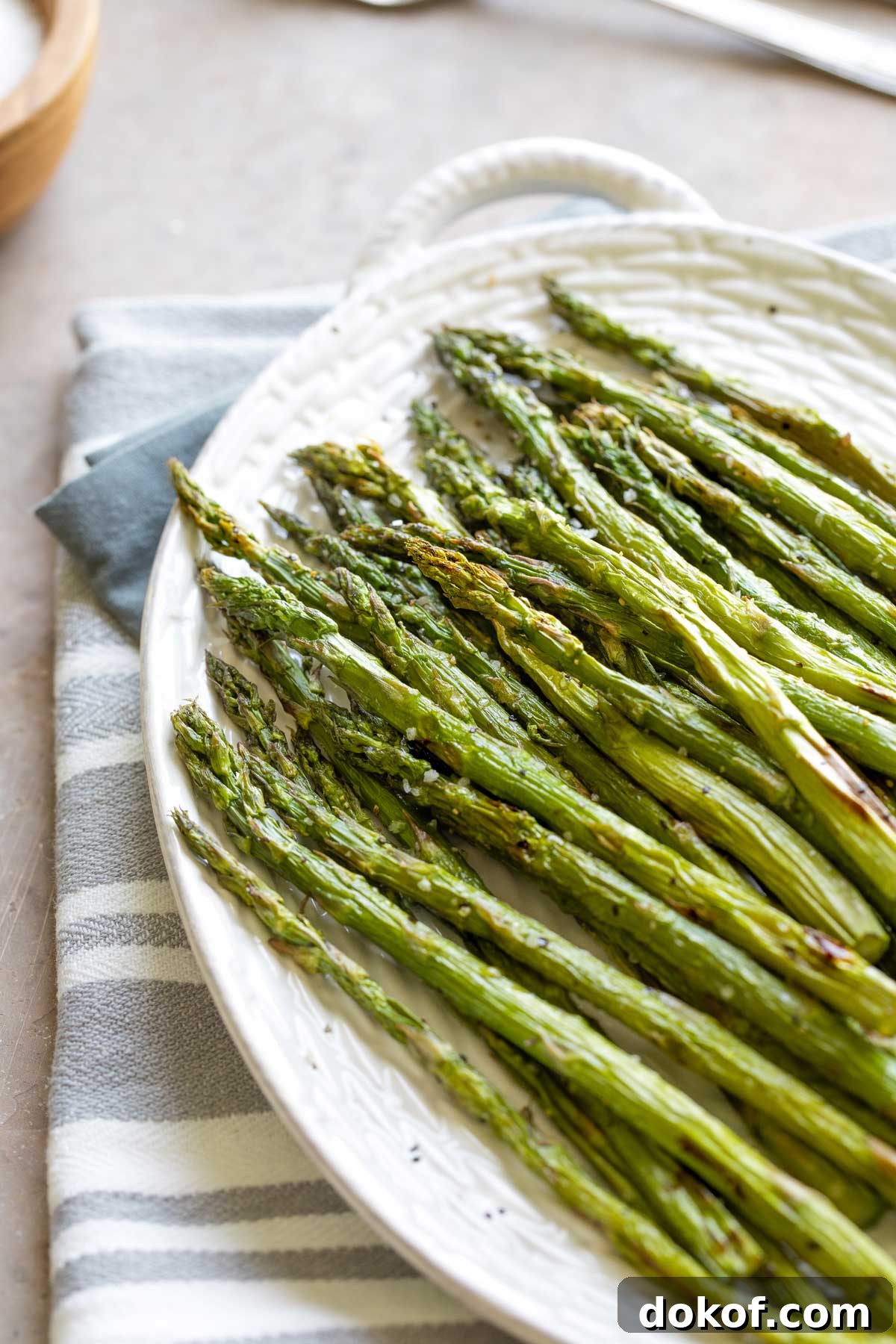 Cooked asparagus piled on white platter.