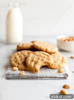 peanut butter cookies piled on small cooling rack. front cookie with bite taken out of it