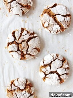 gingerbread crinkle cookies coated in powdered sugar on parchment paper