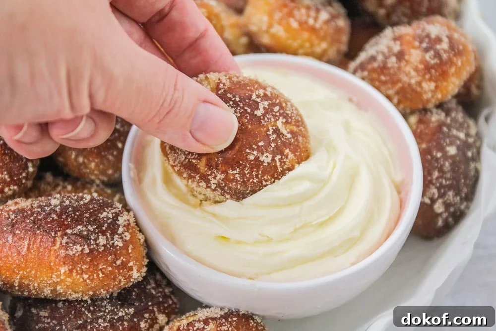 This copycat recipe for Auntie Anne's Cinnamon Sugar Pretzel Bites makes pretzels that are super soft on the inside and bursting with cinnamon sugar flavor on the outside! Dipping cinnamon pretzel bite into cream cheese dip