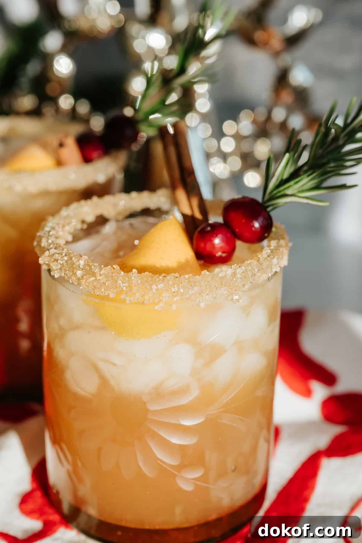 spiced pomegranate cranberry holiday margarita garnished with rosemary, cranberries, and orange peel.