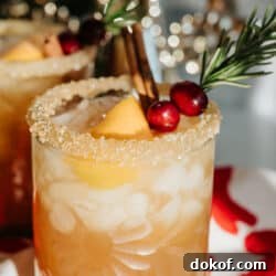 spiced pomegranate cranberry holiday margarita garnished with rosemary, cranberries, and orange peel.