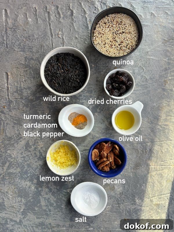 overhead image of the ingredients needed for wild rice recipe with quinoa. Each ingredient is in it's own small bowl and labeled with white text.
