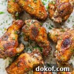 Baked dry rub chicken wings made with a brown sugar rub topped with finely chopped parsley on a sheet of parchment paper.