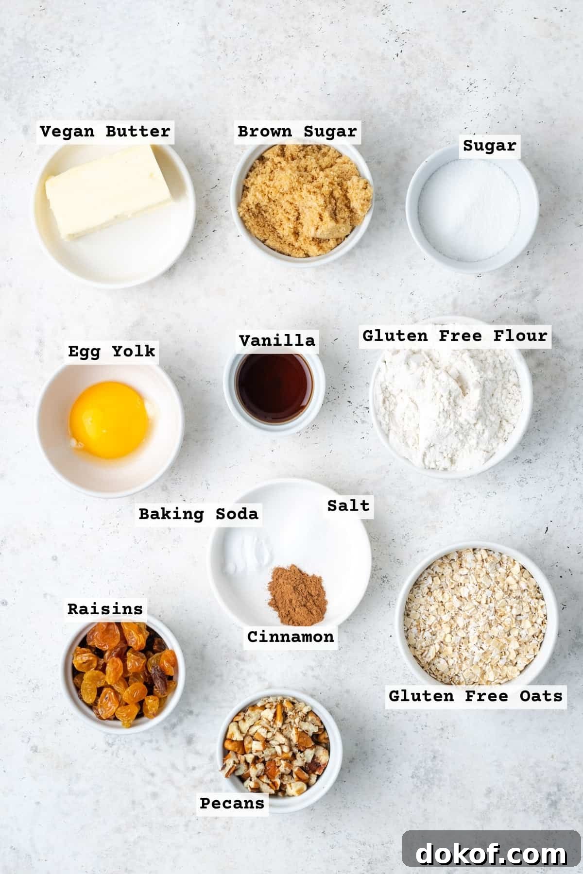 Ingredients for gluten free oatmeal raisin cookies on a white table.