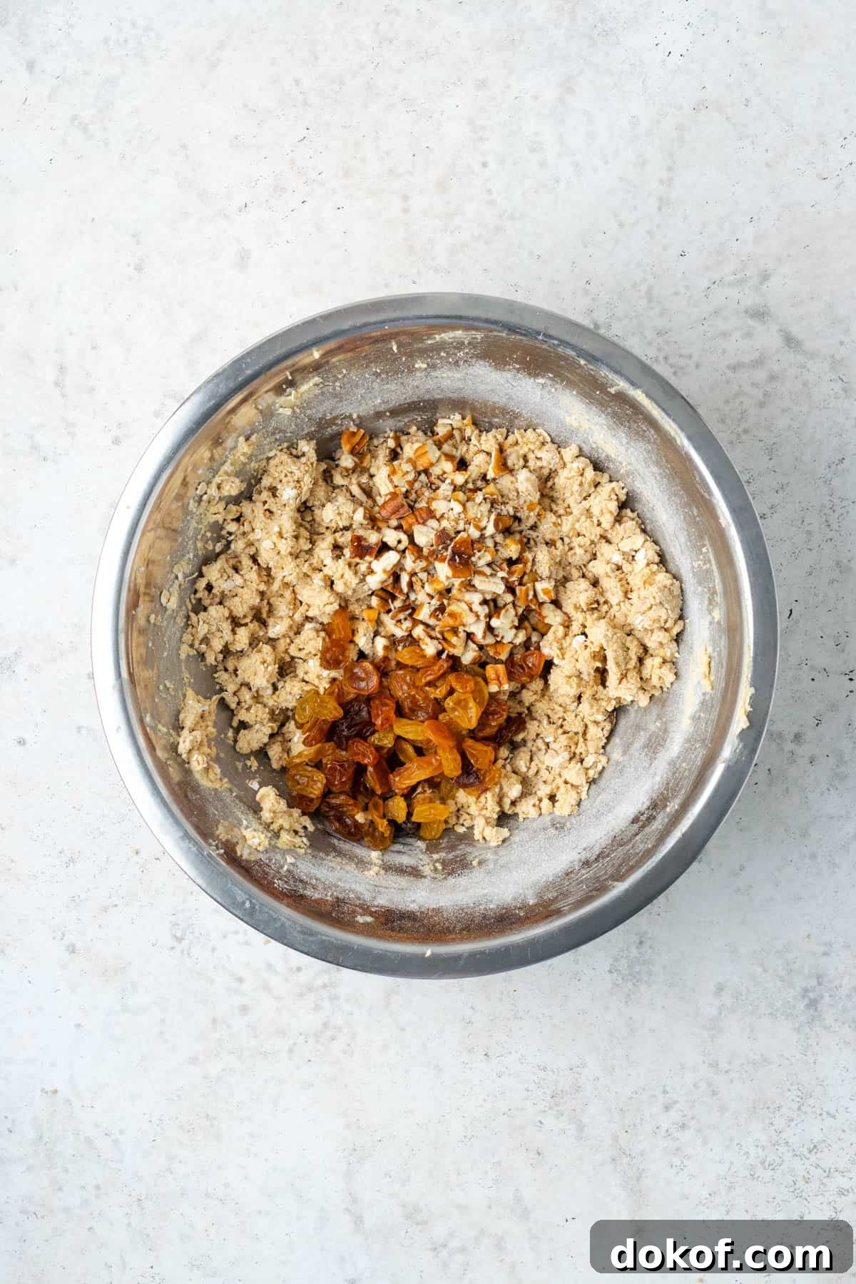 Raisins and pecans being added to the oatmeal cookie dough.