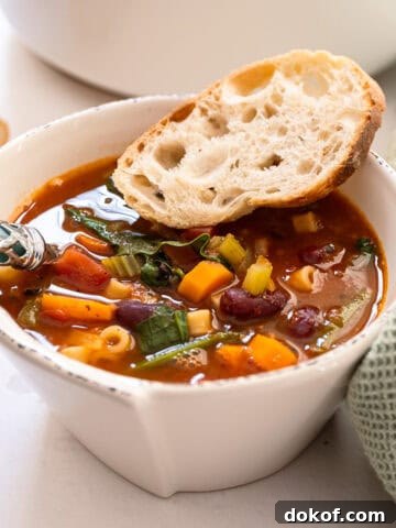 A bowl of minestrone with a piece of Italian bread.