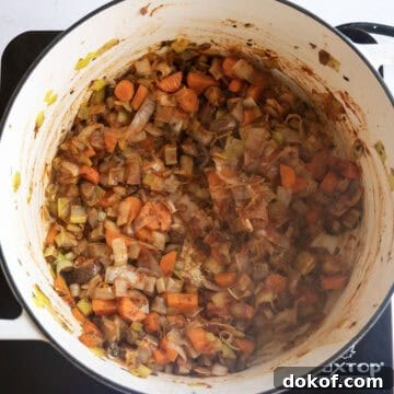 Sauteing vegetables with tomato paste caramelizing in a pot.