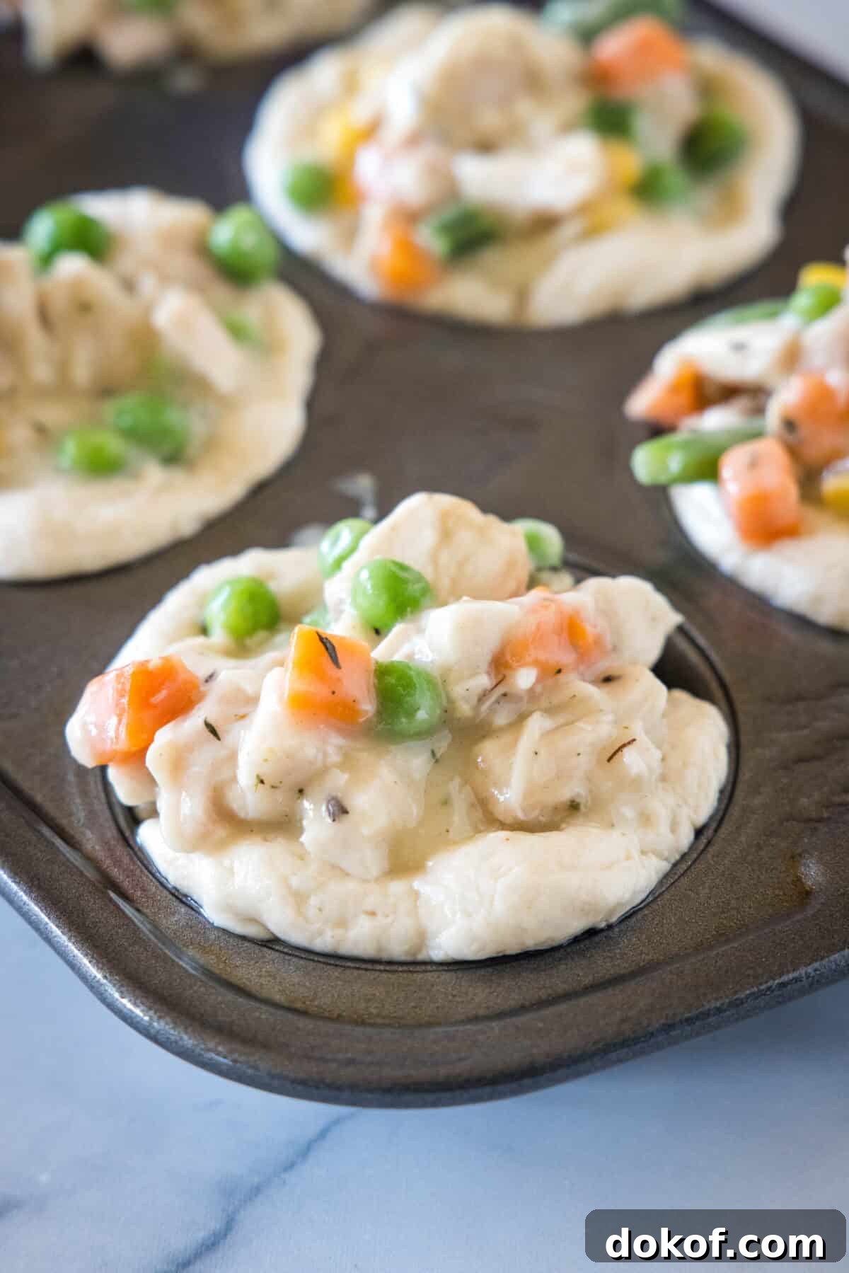Unbaked mini pot pies in a muffin tin.