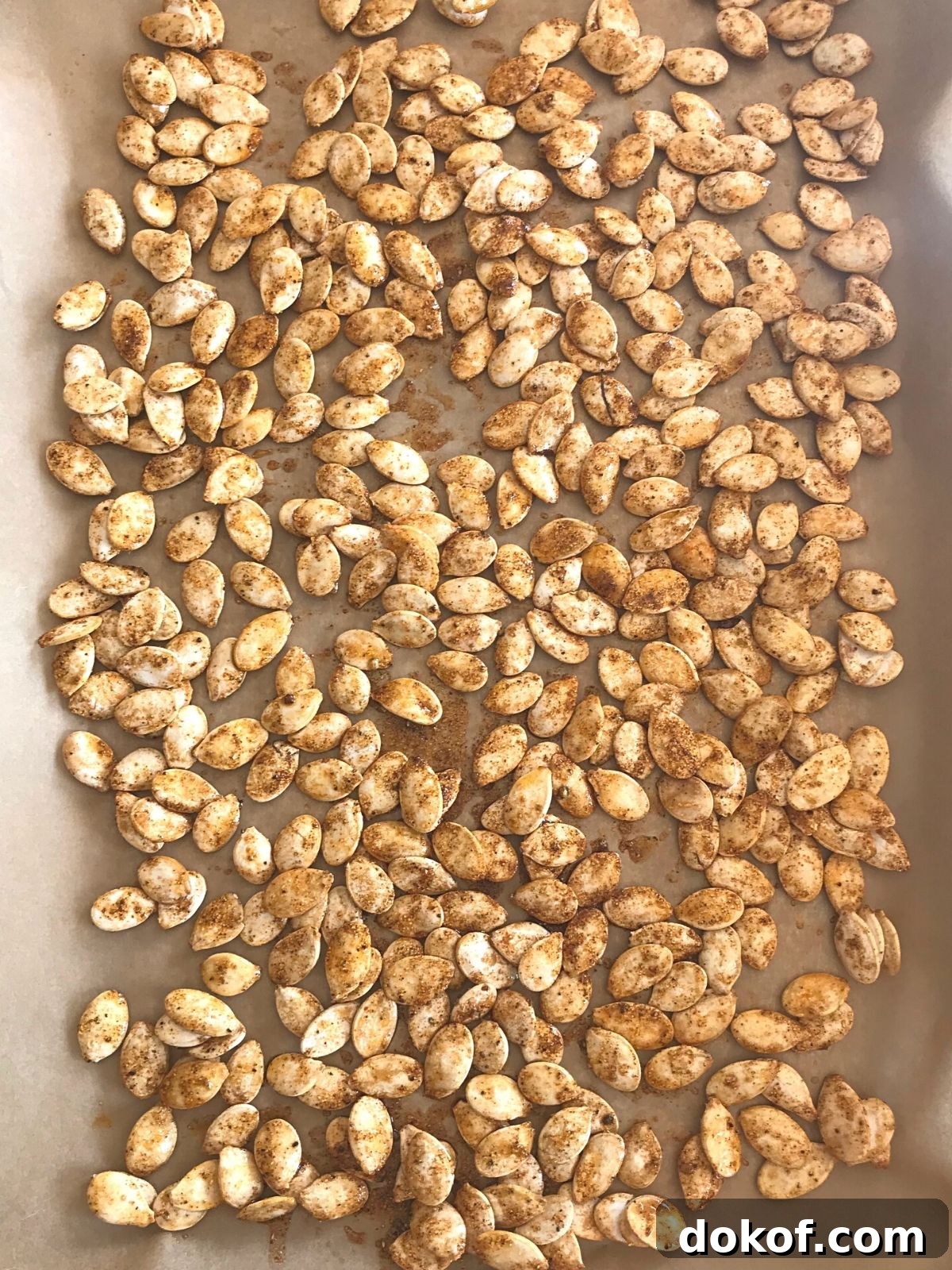 pumpkin seeds spread on a baking sheets to be baked.