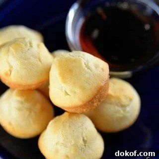 Plate of golden pancake muffins with dipping bowl of maple syrup.
