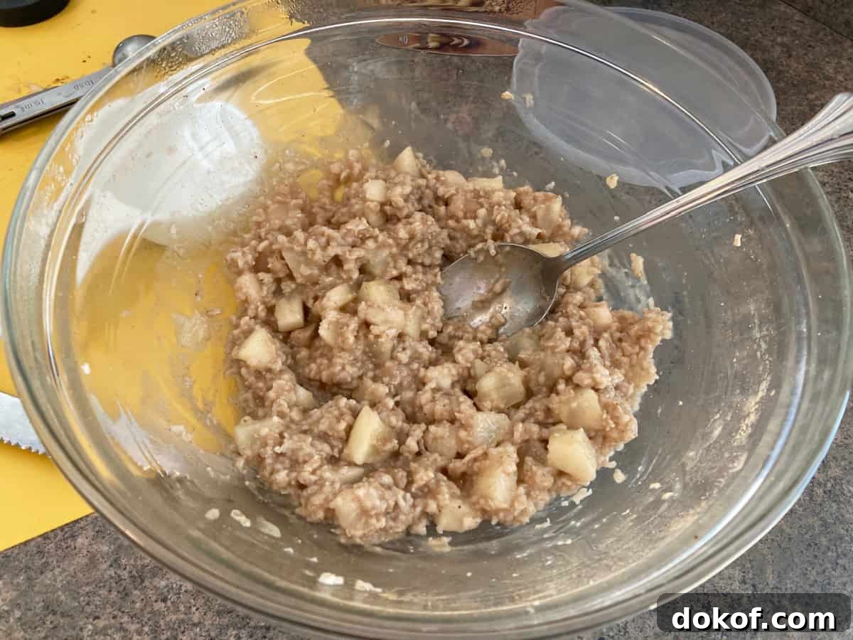 Stirring bowl of microwave apple pie oatmeal with spoon.
