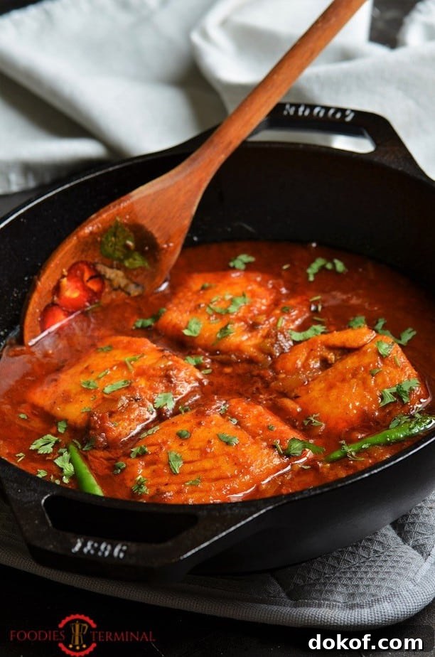 Indian Salmon Curry in a wok with a wooden spatula 